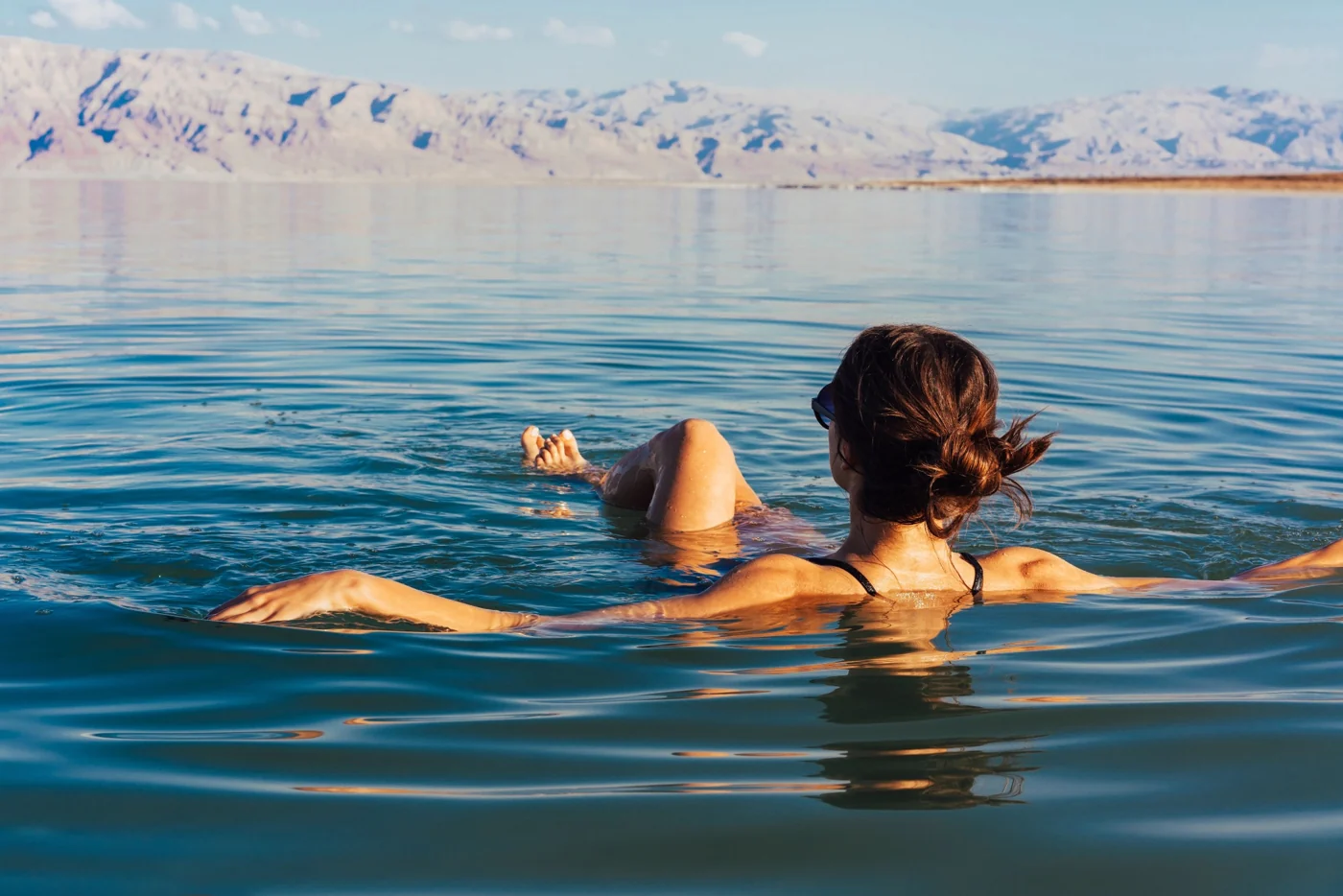 Eine Frau schwebt entspannt auf dem Wasser des Toten Meeres